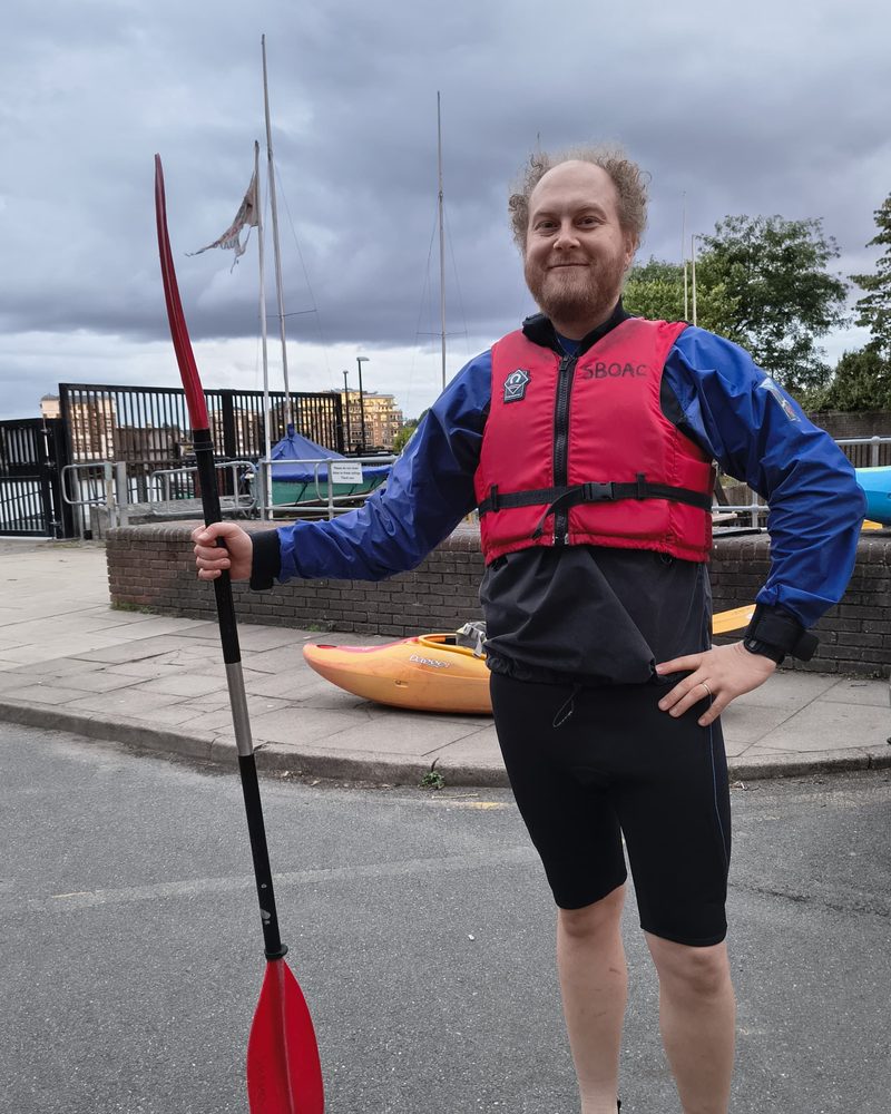 Jack in a buoyancy aid holding a paddle, ready to kayak