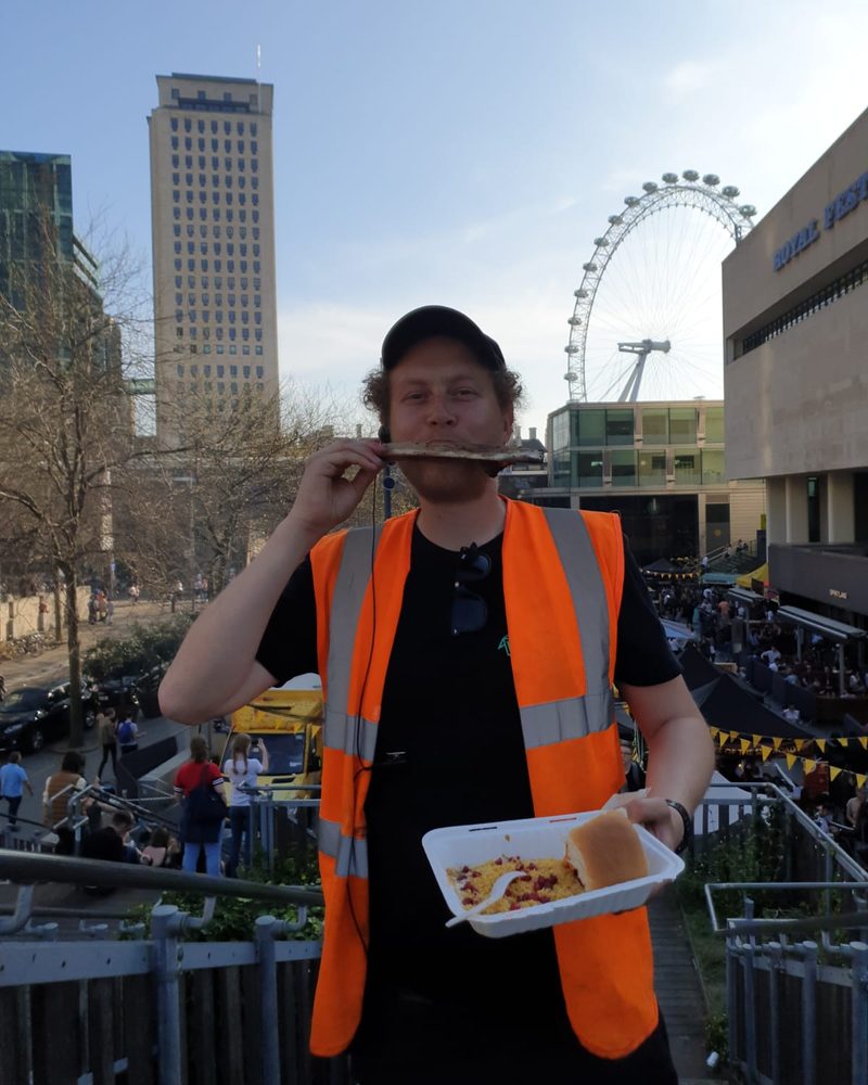 Jack in a hi-vis vest on the Southbank, holding a bone and street food